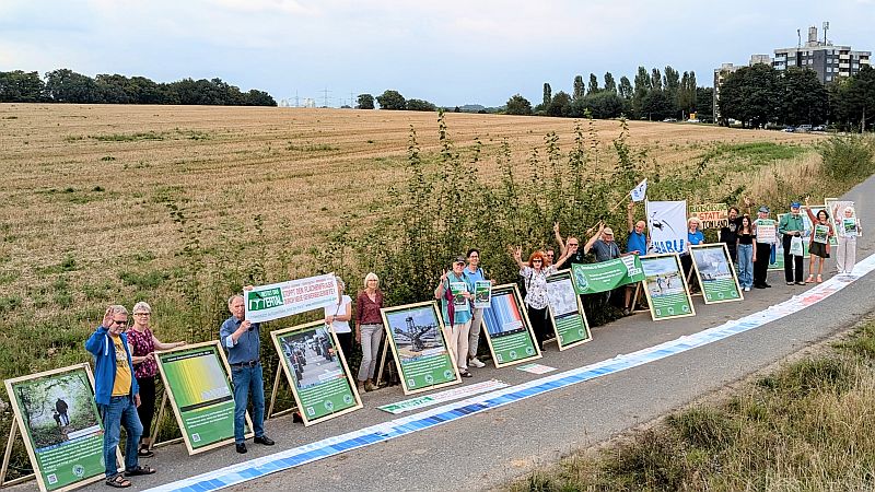 Klimabündnis demonstriert mit Plakaten und Menschenkette vor der Landwirtschafsfläche Buschfeld für deren Erhalt