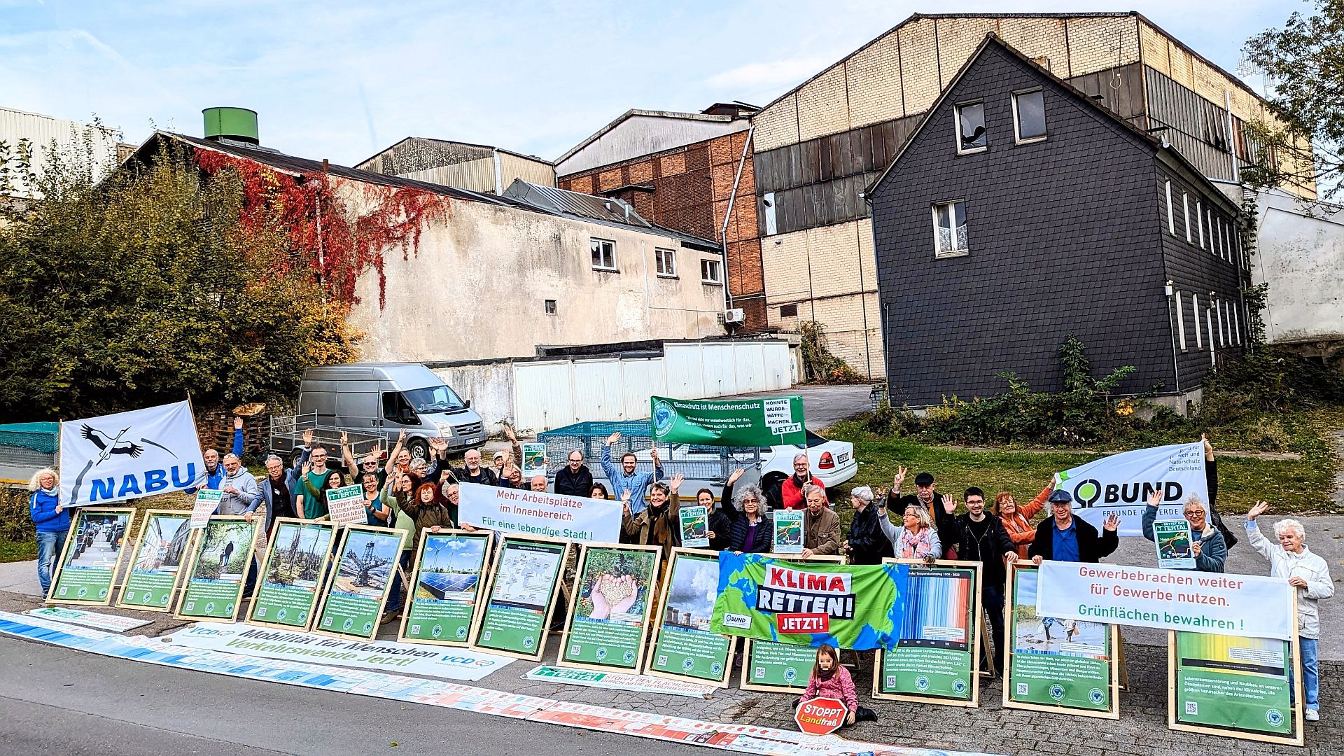 Klimabündnis demonstriert mit Plakaten und Menschenkette vor einer Gewerbebrache für deren Weiternutzung als Gewerbefläche
